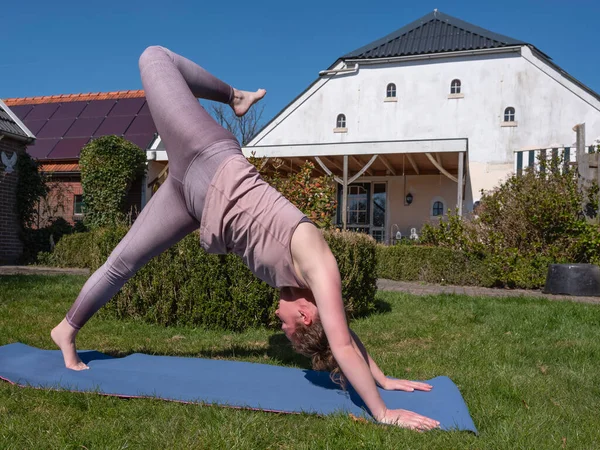Молода жінка займається вправами йоги в саду вдома, дика річ позує — стокове фото