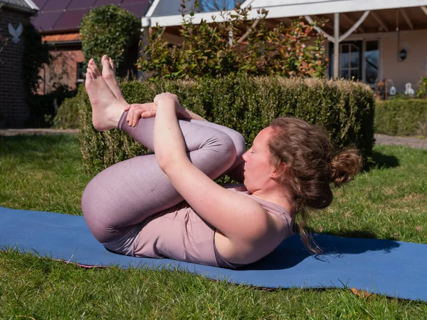 Молода жінка займається вправами йоги в саду вдома, в повітрі звільняє позу — стокове фото