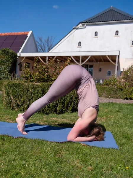 Mujer joven haciendo ejercicios de yoga en el jardín en casa. posada de cabeza — Foto de Stock