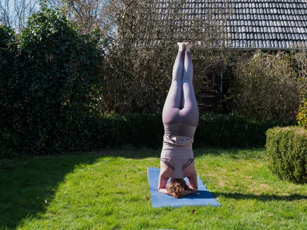 Mujer joven haciendo ejercicios de yoga en el jardín en casa — Foto de Stock