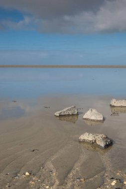 Paesens moddergat 'taki boş denizin rahatlatıcı bir resmi, önplanda büyük bir kaya, deniz ve gökyüzü.