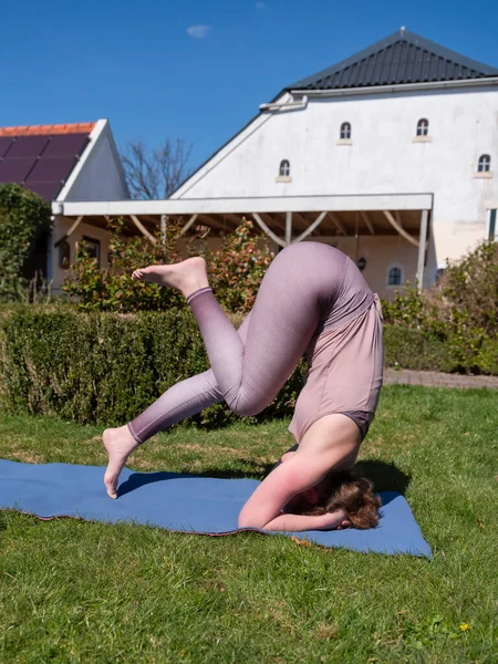 Молода жінка займається вправами йоги в саду вдома. завіса позу — стокове фото