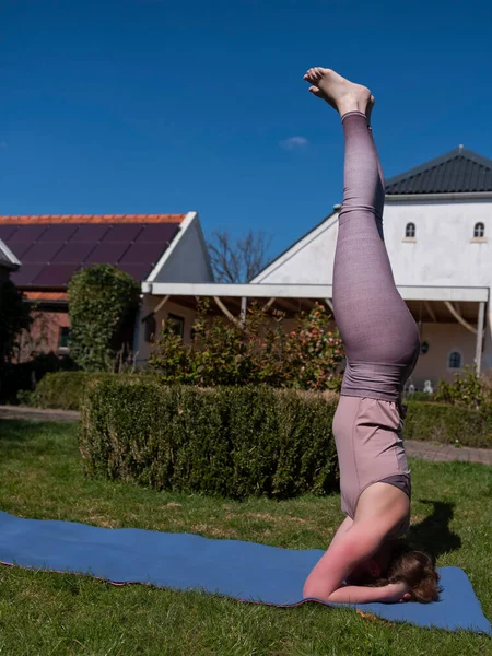 Mujer joven haciendo ejercicios de yoga en el jardín en casa. posada de cabeza — Foto de Stock