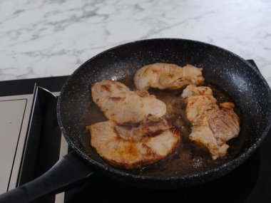 Domuz pirzolası pişirilen bir indüksiyon tabağında tava.