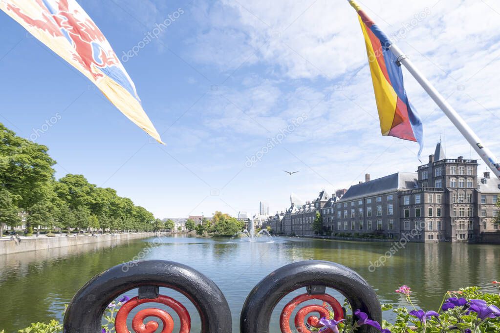 View to the historical Binnenhof with the Hofvijver lake, flags and flowers in foreground, focus on foreground, by day in The Hague, The Netherlands.