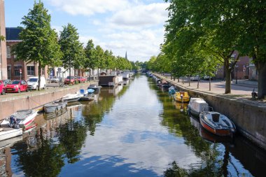 Lahey, Hollanda - 15 Mayıs 2020: Tekne ve ağaçların yansımasıyla kanal, Lahey, Hollanda 'da araba ve evlerle dolu sokak