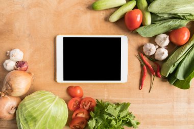 Tablet ile taze sebze üstten görünüm dokunma bilgisayar gadget'ı ahşap masa arka plan.