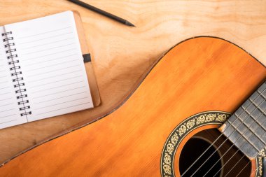Ahşap masa arka plan üzerinde boş defter ile akustik gitar Üstten Görünüm. 