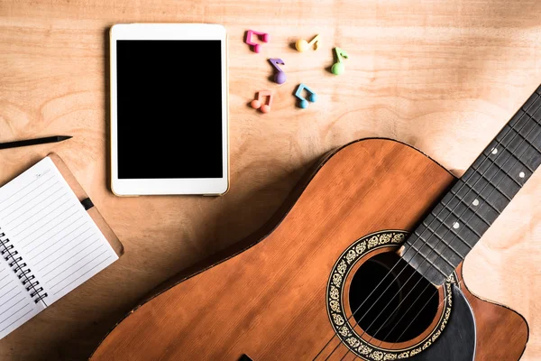 Tablet ile akustik gitar üstten görünüm dokunma bilgisayar gadget'ı ahşap masa arka plan.