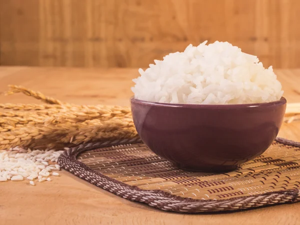 Arroz cocido en tazón con grano de arroz crudo y planta de arroz seco sobre fondo de mesa de madera . —  Fotos de Stock