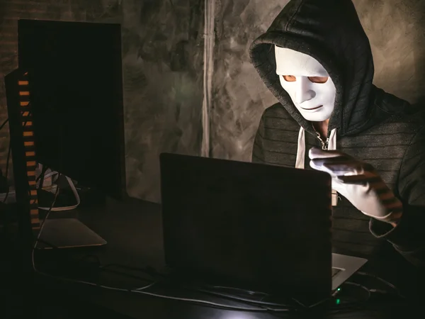 Počítačový hacker - muž v košili s kapucí s maskou krádeže dat z notebooku — Stock fotografie
