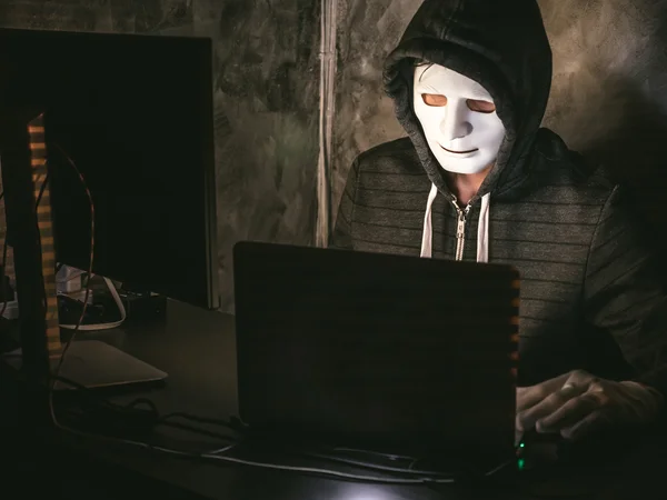 Υπολογιστή hacker - άνθρωπος σε φούτερ με κουκούλα πουκάμισο με μάσκα κλοπή των δεδομένων από το φορητό υπολογιστή — Φωτογραφία Αρχείου