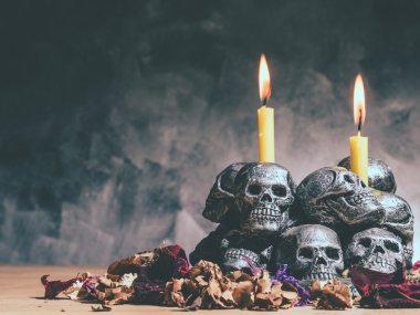 Mum yakma ve koyu arka plan üzerinde kurutulmuş çiçeklerle kafatasları.