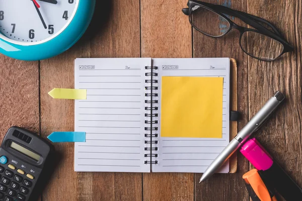 Draufsicht auf Notizbuch mit Bürobedarf, Uhr und Brille auf Holztischhintergrund. — Stockfoto