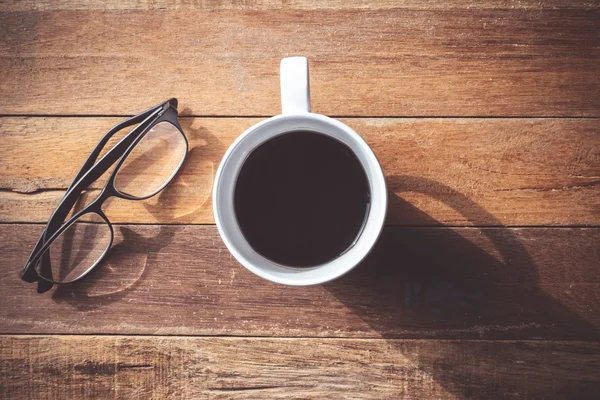 Vista superior de la taza de café con gafas sobre fondo de mesa de madera . —  Fotos de Stock