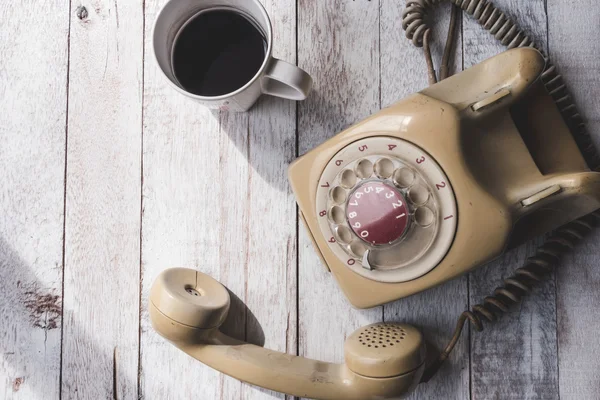 Top view of Old telephone with coffee cup on white wooden table background. — Stock Photo, Image