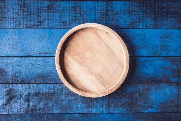 Вид сверху деревянной тарелки на синем деревянном фоне . — стоковое фото