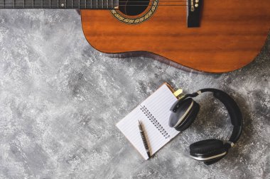 Grunge arka plan üzerinde kulaklık, kalem ve defter ile gitar Üstten Görünüm