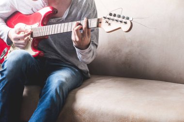 Casual genç adam evde kanepede gitar çalmak.