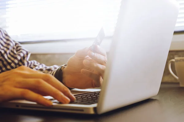 Close up of male hands using Laptop and holding credit card on the desk,toned with sunlight. — Stock Photo, Image