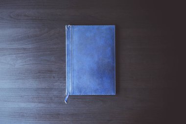 Eski mavi kitap görünümü siyah masa üzerinde ana sayfa.