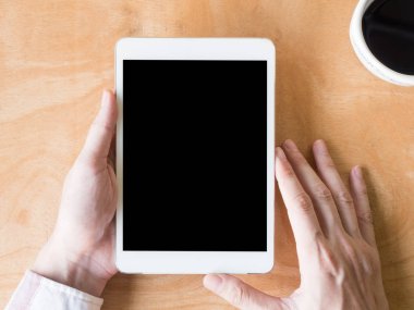 Erkek el ahşap masa üzerinde kahve fincanı ile tablet kullanarak Üstten Görünüm.