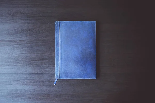 Draufsicht auf das alte blaue Buch auf dem schwarzen Schreibtisch. — Stockfoto