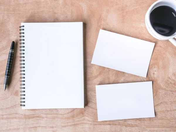 Vista superior de notebook em branco com cartões de fotos em branco e xícara de café na mesa de madeira . — Fotografia de Stock
