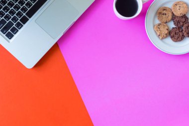 Laptop ile kahve fincanı ve çerezleri renkli arka plan üzerinde. Metin için boş alan