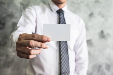 Grunge arka plan üzerinde beyaz boş kartı tutan işadamı yakın çekim