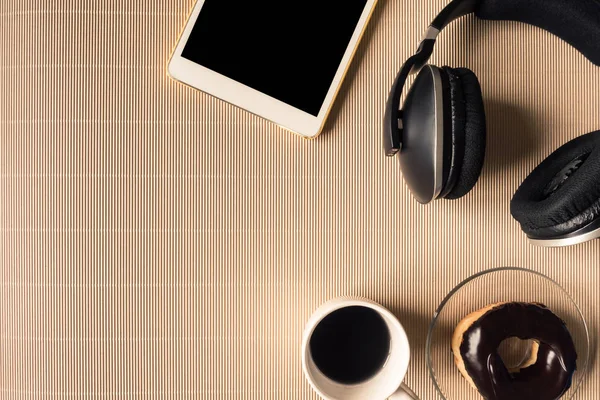 Top view of headphones with tablet, coffee cup and donut on table. Free space for text — Stock Photo, Image