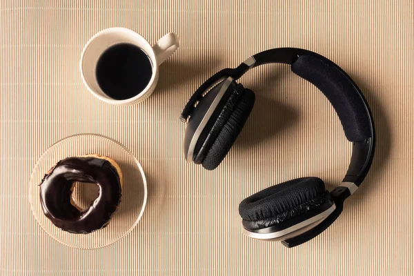 Top view of headphones with coffee cup and donut on table. — Stock Photo, Image