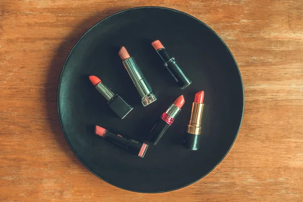 Vista superior de batons coloridos na placa preta sobre a mesa de madeira. Maquiagem e beleza conceito — Fotografia de Stock