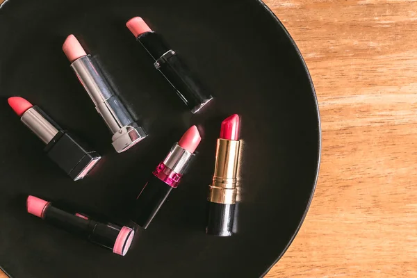 Bovenaanzicht van kleurrijke lippenstift op de zwarte plaat over de houten tafel. Make-up en Beauty concept — Stockfoto