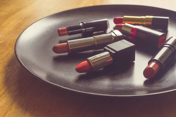 Kleurrijke lippenstift op de zwarte plaat over de houten tafel. Make-up en Beauty concept — Stockfoto