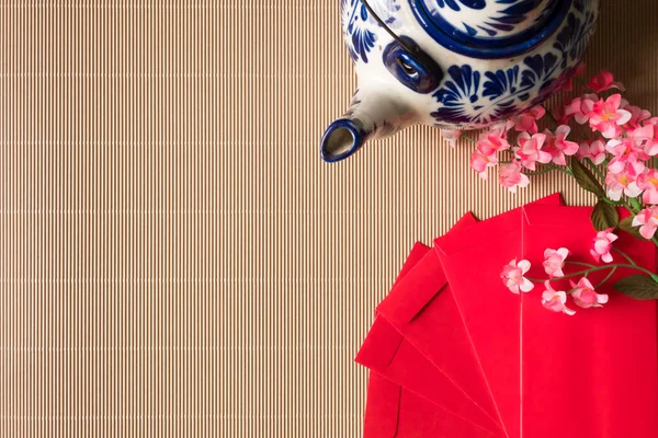 Widok z góry chińskie śliwkowe kwiaty z czerwonym pakietów i czajnik na stół, koncepcja chiński nowy rok, ilość wolnego miejsca dla tekstu — Zdjęcie stockowe