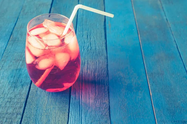 Coquetel vermelho com cubos de gelo em fundo de prancha de madeira pintada de azul . — Fotografia de Stock