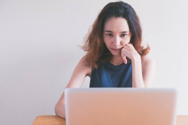 Masanın üzerinde bir dizüstü bilgisayar kullanarak rahat genç kadın.