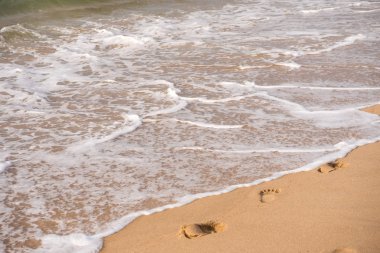 Kumlu bir plaj üzerinde ayak izleri. Seyahat kavramı