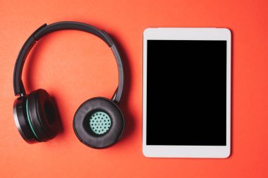 Tablet PC'de turuncu bir arka plan ile modern kulaklıklar.