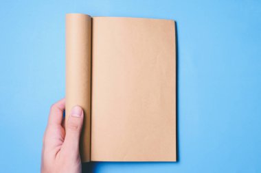 Boş bir kitap kopya alanı ile hazır hazır metin için mavi arka plan üzerinde tutan eller Üstten Görünüm.