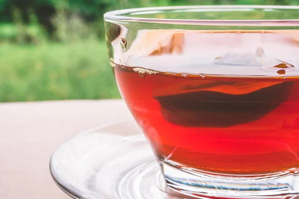Чашка чая на деревянном столе, пакетик чая в стекле, фон природы . — стоковое фото