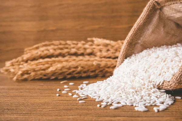 Close up of raw rice in burlap sack on wooden table. — Stock Photo, Image