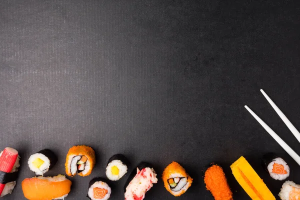 Siyah arka plan, Japon yemekleri üzerine üstten görünüm Sushi seti ve yemek çubukları. Metin için boş alan