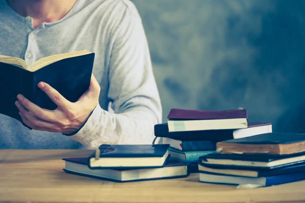 Primer plano de un hombre leyendo un libro sobre la mesa de madera. Tono vintage — Foto de Stock