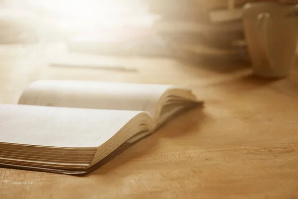 Nahaufnahme eines offenen Notizbuchs auf Holzschreibtisch, weicher Fokus, grelles Sonnenlicht, Vintage-Ton. — Stockfoto