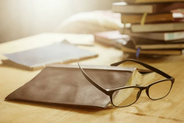 Occhiali con libri sul tavolo di legno, Focus morbido, Luce del sole bagliore, tono Vintage . — Foto Stock