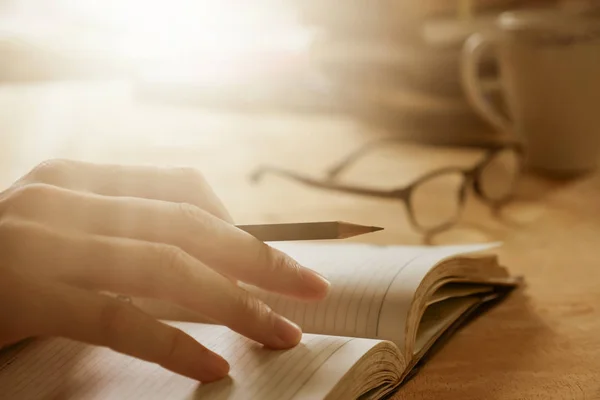 Close up of male hand writing in notebook on wooden desk, Soft focus, Flare sun light,Vintage tone. — Stock Photo, Image