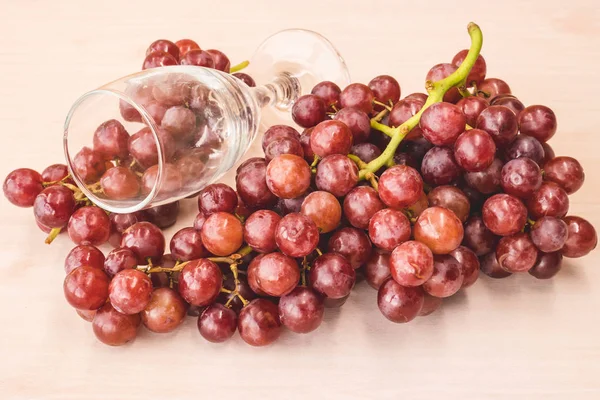 Uvas rojas con copa de vino en la mesa de madera . — Foto de Stock