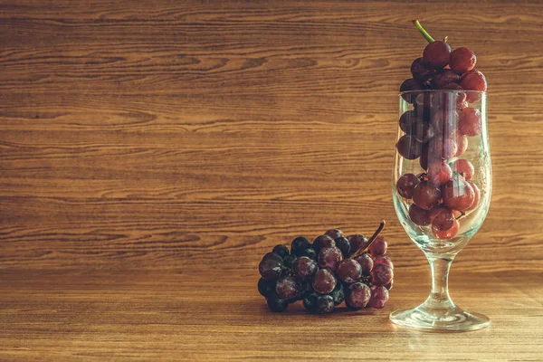 Червоний виноград у склянці на дерев'яному столі. Вільний простір для тексту — стокове фото